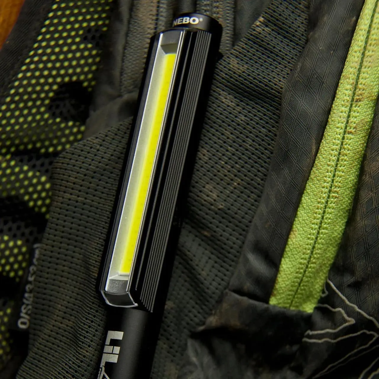 Nebo Lil Larry pocket flashlight close-up resting on a textured black and green backpack